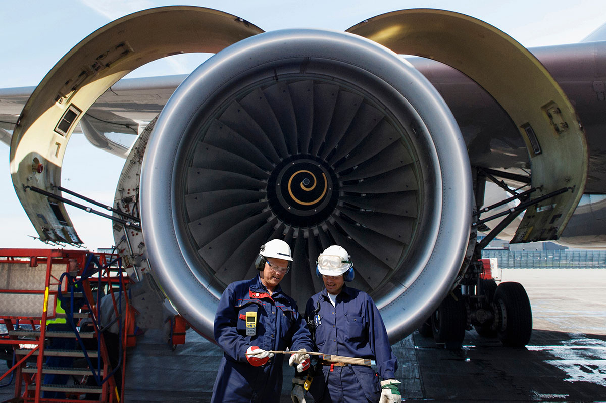 airplane mechanics in front of jumbo jet engine